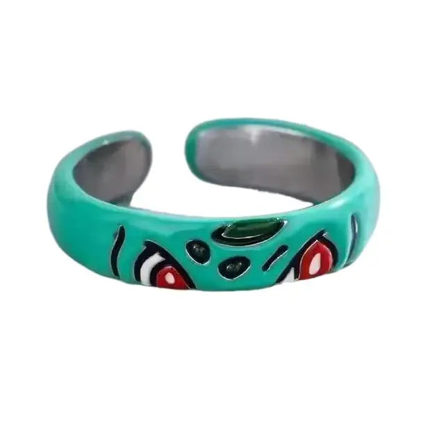 Bague pokémon bulbizarre en alliage métallique bleu sarcelle avec design unique yeux rouges et noirs stylisés