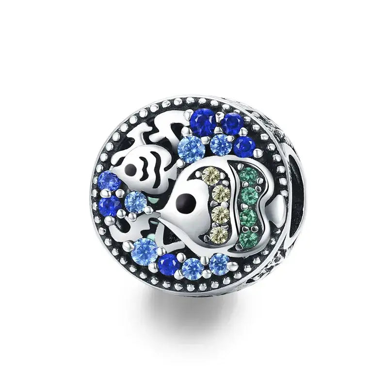 Charme argent circulaire avec motif crâne et os croisés orné de pierres bleues, vertes et jaunes pour bracelet océan