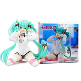 Figurine hatsune miku aux cheveux teal avec oreilles de chat en chemise blanche posée à côté de son packaging pour fans d’anime l’icône vocaloïde