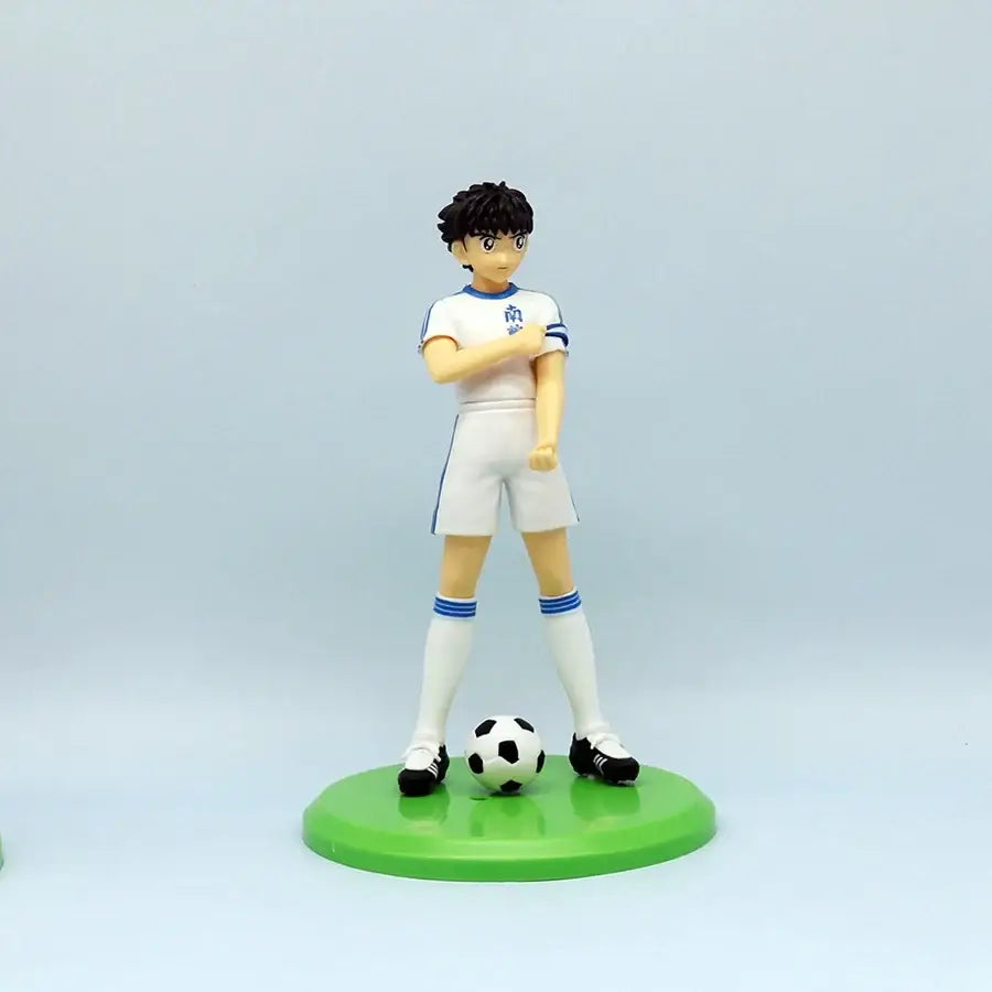Figurine anime olive et tom captain tsubasa en blanc et bleu sur socle vert avec ballon noir et blanc l’univers d’olive
