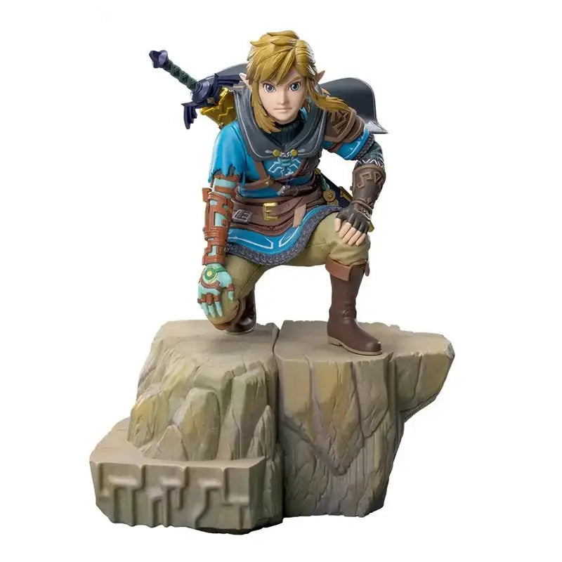 Figurine link tears of the kingdom avec cheveux dorés en tunique bleue et armure marron posée sur socle rocheux