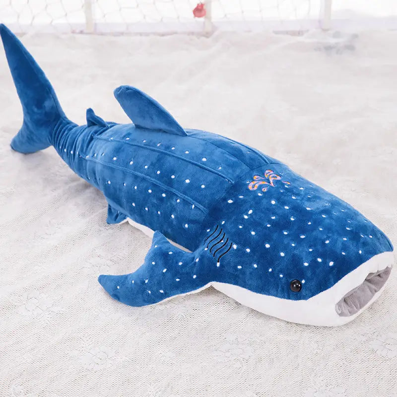 Grande peluche requin bleu en tissu doux avec taches blanches et motif rose brodé sur le côté