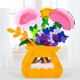 Un jeu construction fleurs en pot avec vase en feutre jaune vif et compositions florales uniques en tissu rose violet et bleu