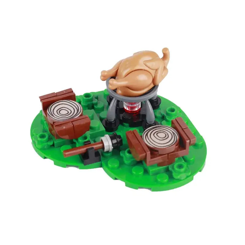 Lego moc medieval avec une dinde en plastique tan rôtissant sur un grill noir et rouge sur base verte avec tables pique-nique marron