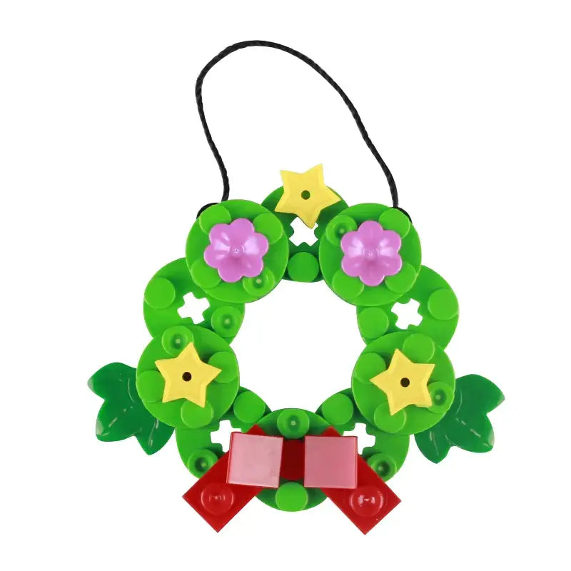 Lego moc décor de noël en plastique vert avec fleurs roses, étoiles jaunes, feuilles vertes et nœud rouge