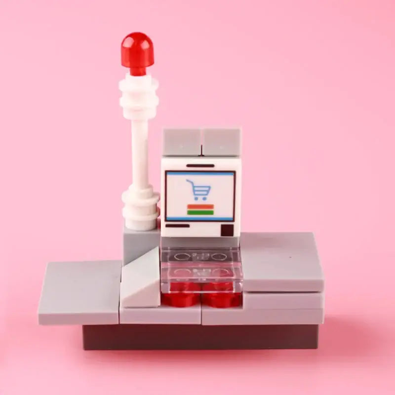 Comptoir de caisse lego moc gris avec poteau rouge et écran affichant une icône de caddie pour lego fruits et lego legumes