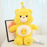 Peluche doudou bisounours calinours jaune vif avec emblem de soleil souriant et chapeau anniversaire joyeux