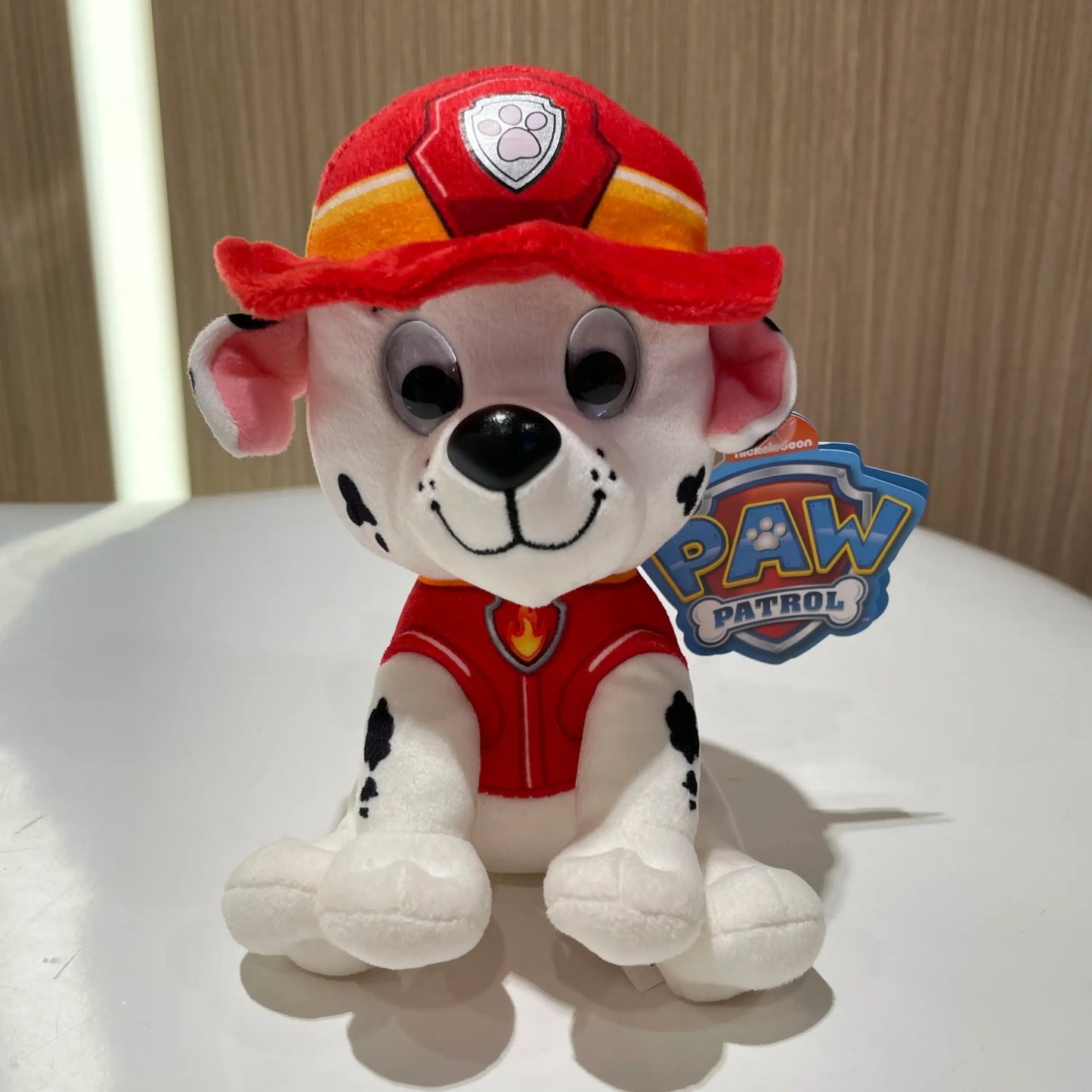 Peluche pat patrouille représentant marshall avec corps blanc à taches noires portant un chapeau et gilet de pompier rouge