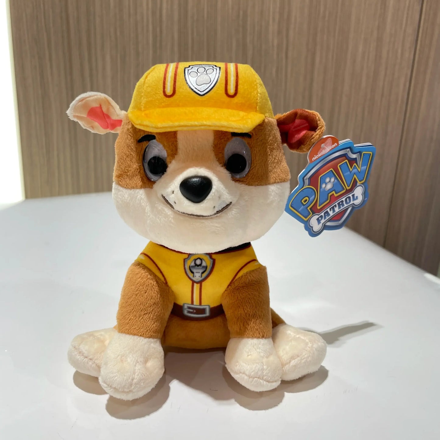 Peluche pat patrouille rubble avec pelage beige et blanc, casque jaune et gilet de chantier, héros canin préféré