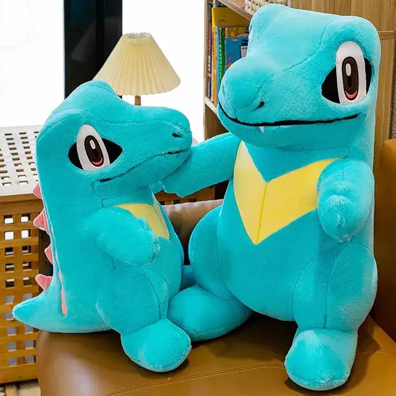 Peluche kaiminus totodile avec peluches turquoise et jaune squirtle et blastoise assises sur un canapé