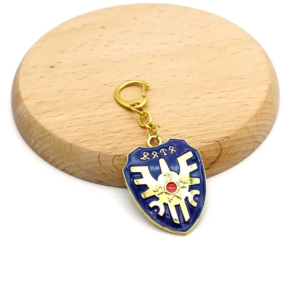 Porte-clé zelda en émail bleu et or en forme de bouclier avec une pierre rouge au centre épée bouclier zelda
