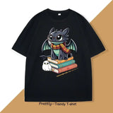 T-shirt anime noir avec illustration de toothless portant une écharpe rayée assis sur des livres avec un hibou à côté
