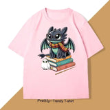 T-shirt anime rose avec illustration de toothless portant lunettes et écharpe, sur livres avec hibou, t shirt manga drôle dragon