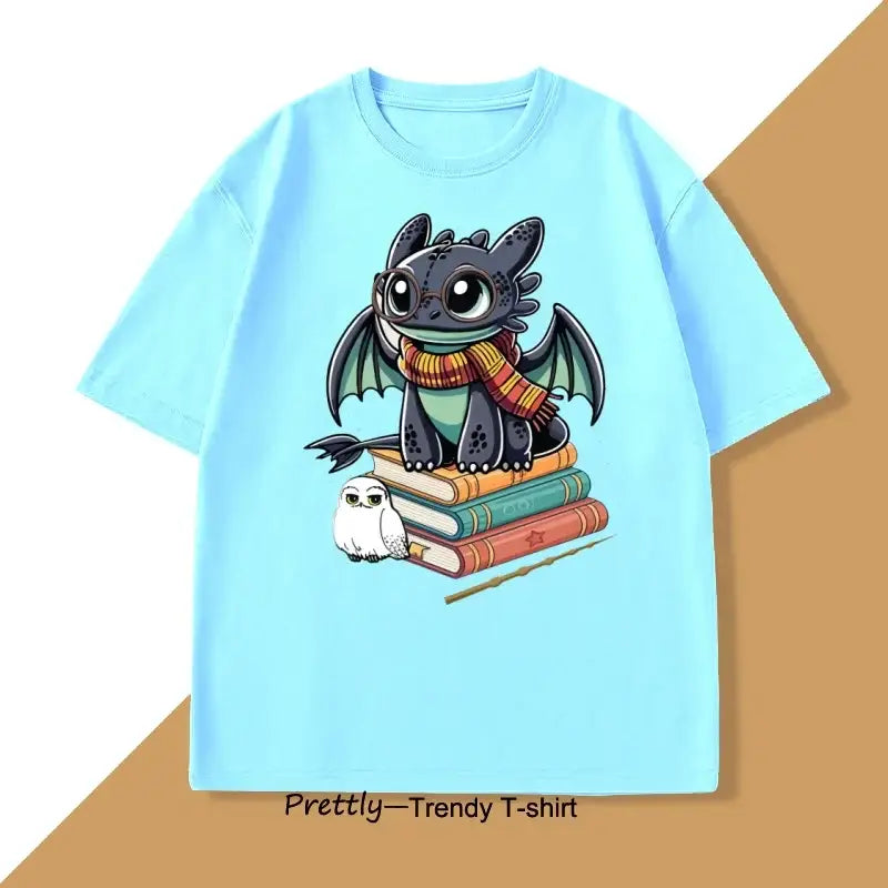 T-shirt anime bleu clair avec dragon funny portant lunettes et écharpe, assis sur livres avec hibou et baguette magique