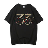 T-shirt clair obscur expedition coton premium noir à manches courtes avec graphisme doré 33 et confettis floraux rouge et blanc