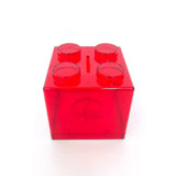 Tirelire lego unique en plastique rouge translucide en forme de brique avec quatre plots circulaires et fente à pièces